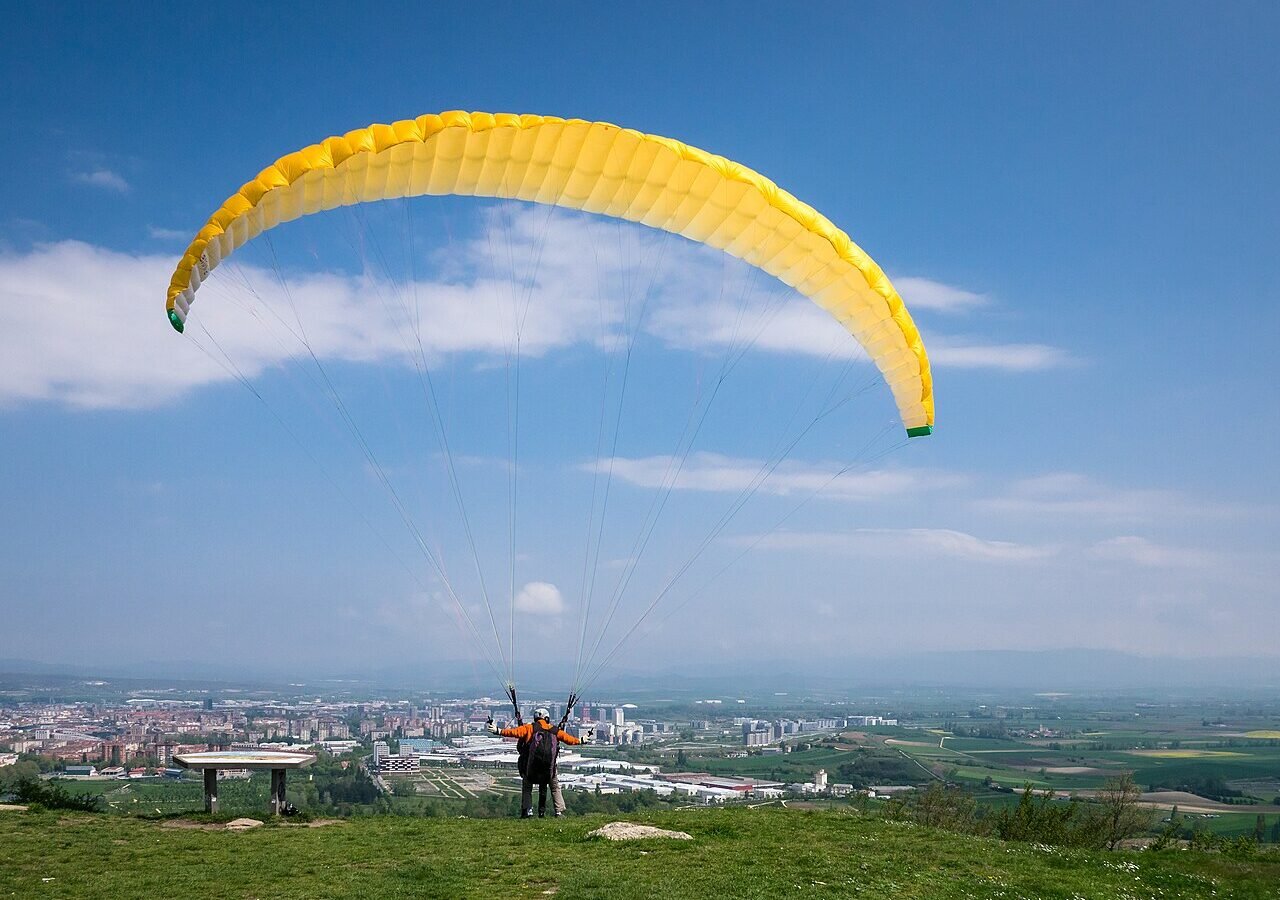 Parapente em voo duplo sobre paisagem verde