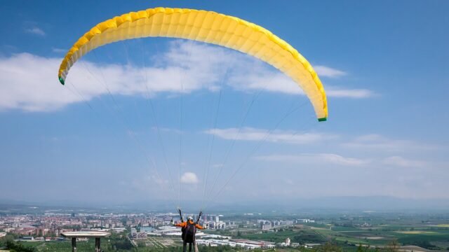 Parapente em voo duplo sobre paisagem verde